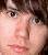Pixelated close-up of a person's face with light skin tone, dark hair, and visible eye details including eyelashes and eyebrow.