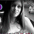 Black-and-white image of a woman with long hair smiling, wearing a sleeveless top, with a purple circular element in the top-left corner.