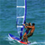 Pixelated 50x50 static icon showing a person windsurfing on blue water with a sail, featuring brown skin tone and colorful board details.
