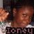 A pixelated image of a person with dark hair wearing a white top, holding up two hands near their head in a gesture.