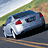 Pixelated image of a blue sedan with red accents on a road, green hillside, and sky background.
