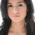 Pixelated close-up of a person with long dark hair, light skin, and visible facial features including eyes, nose, and lips against a plain background.