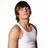 Pixelated image of a person with short brown hair wearing a white sleeveless shirt, standing against a plain white background.