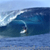 Pixelated static image of a surfer riding a large ocean wave under a light blue sky, with visible water spray and motion blur effects.