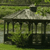 A pixelated static image of a house with a gabled roof, dark columns, and green surroundings.