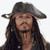 Pixelated static image of a person with long dark hair wearing a wide-brimmed dark hat, closed eyes, and a neutral expression against a plain white background.