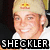 Pixelated image of a smiling person with light hair wearing a beige cap and white shirt, text "SHECKLER" below.