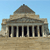Pixelated image of a classical building with columns and a dome under a light blue sky.