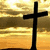 Two black crosses stand against a golden sunset sky with horizontal cloud layers, and the word 'Believe' appears in white text at the bottom center.