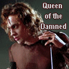A shirtless person with long curly hair holds a microphone, with text reading 'Queen of the Damned' in brown letters on a dark background.