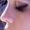 Close-up profile view of a person's face showing nose, lips, and eye with eyelashes, dark hair visible on left, skin tone light pinkish-brown.