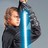 Pixelated static image of two figures holding a glowing blue lightsaber-like object against a gray background.