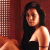 Pixelated image of a person with long dark hair wearing a black sleeveless top, positioned against a checkered and solid brown background.