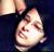 Pixelated close-up of a person's face with light skin, dark eyes, and closed mouth against dark background.
