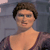 Pixelated image of a person with short brown hair wearing a dark purple sleeveless top against a gray background.