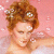 A pixelated portrait of a person with curly brown hair styled in an updo, adorned with white floral accessories, against a pink background with scattered white dots.
