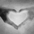 A grayscale heart-shaped icon with a bright white center and dark gray border, set against a light gray background.