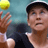 Static 48x48 pixel icon showing a tennis player mid-serve with a yellow ball in motion, wearing dark clothing and a cap against a blurred background.