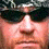 Pixelated close-up of a face with dark hair, light skin tone, and visible nose mouth area against blurred background.
