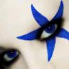 Close-up of a face with blue star-shaped eye makeup and a visible blue eye.