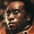 Pixelated static image of a person's face with brown hair and an orange garment, rendered in low-resolution 256x256 pixels with visible dithering and color blending.