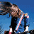 A 48x48 pixel animated buddy icon featuring a cartoon character with long brown hair against a blue sky background, alongside green text reading "Original Icons .com" on a dark green backdrop.