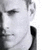 A grayscale close-up of a person's face in profile, showing the right side with visible ear and neck, against a white background.