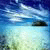 Pixelated landscape with blue sky, white clouds, and light blue water reflecting a dark landmass.