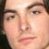 Pixelated close-up of a person's face showing eyes, nose, and mouth with light skin tone against dark background.