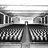 Black-and-white pixelated image showing a bridge with two symmetrical sections and a central vertical element, likely a tower or support structure, with a patterned foreground and background.