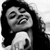 Black-and-white pixelated image of a person with long dark hair, closed eyes, and a wide open mouth showing teeth, wearing a light-colored top.