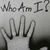 Black-and-white hand with five fingers raised, text "Who Am I?" above, displayed in a of four with one blank