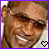 A 49x49 pixel animated contact sheet showing two frames of a smiling person with brown hair and sunglasses, each frame featuring a heart icon in the bottom-right corner that changes color between black-and-white and pink.