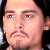 Pixelated close-up of a person's face with dark hair, visible eyebrows, eyes, nose, mouth, and a goatee, set against a dark background.