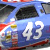 Blue and red race car with white number 43, multiple sponsor logos on side, visible cockpit window, front wheel partially shown.