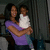 A pixelated static image shows a person in a purple top holding a child in a white outfit against a dark background.