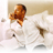 Pixelated static image of a person with brown hair in white clothing holding an object against a light background.