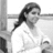 Pixelated grayscale image of a person with long dark hair wearing a white top, positioned against a light background with vertical and horizontal lines.