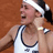 Pixelated static image of a person in athletic attire with a headband, holding an object near their face against a brown background.