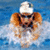 A swimmer in a white cap and goggles performs a breaststroke in blue water with white splashes, alongside yellow-and-blue text elements.