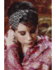A woman in traditional South Asian attire with a red headscarf and jewelry, hands clasped near her face.