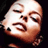 Pixelated static image of a stylized human face with exaggerated features and warm color tones on dark background.