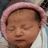 Pixelated close-up of a person wearing a pink headband with closed eyes and a neutral expression.