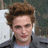 Pixelated close-up of a person with brown hair wearing dark clothing against a blurred background.