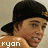 Pixelated image of a person wearing a black cap with a yellow and red emblem, light brown skin, and a brown shirt with white text reading 'kyon' at the bottom left.