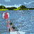 A pixelated animation of a figure in a wetsuit holding a red ball, performing a sequence of movements in a water scene with distant land.