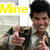 A person in a brown jacket and white shirt gives two thumbs up with a bright smile, yellow 'Mine' text appears top-left.