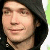 Pixelated close-up of a person with dark hair wearing a dark top, set against a light background with green and white tones.