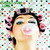 Pixelated static image of a person with closed eyes, light skin tone, and dark hair styled in two large curls on either side of the head.