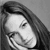 Black-and-white pixelated static image of a person's face with long hair, visible eye and mouth details, and grayscale shading on a plain background.